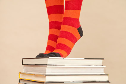 feet in bright socks, standing on pile of books