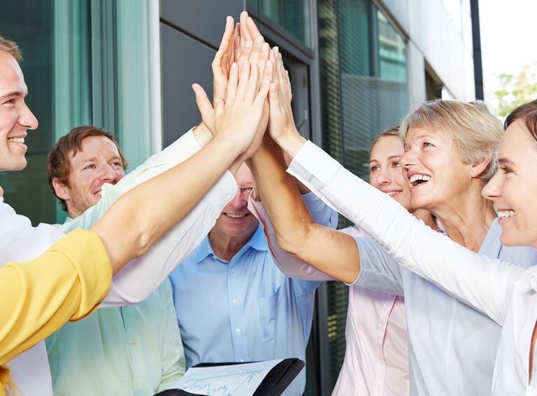 Jubelnde Geschäftsleute geben sich High Five mit den Händen vor dem Büro