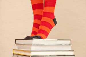 Feet in stripy socks, standing on pile of books